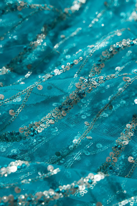 AIzaSyBcstauz-XMPRhEY21AUzeo032pxrXB5Ug - Gold And Silver Sequins With Peacock Blue Thread Wavy Embroidery On Peacock Blue Soft Net Fabric